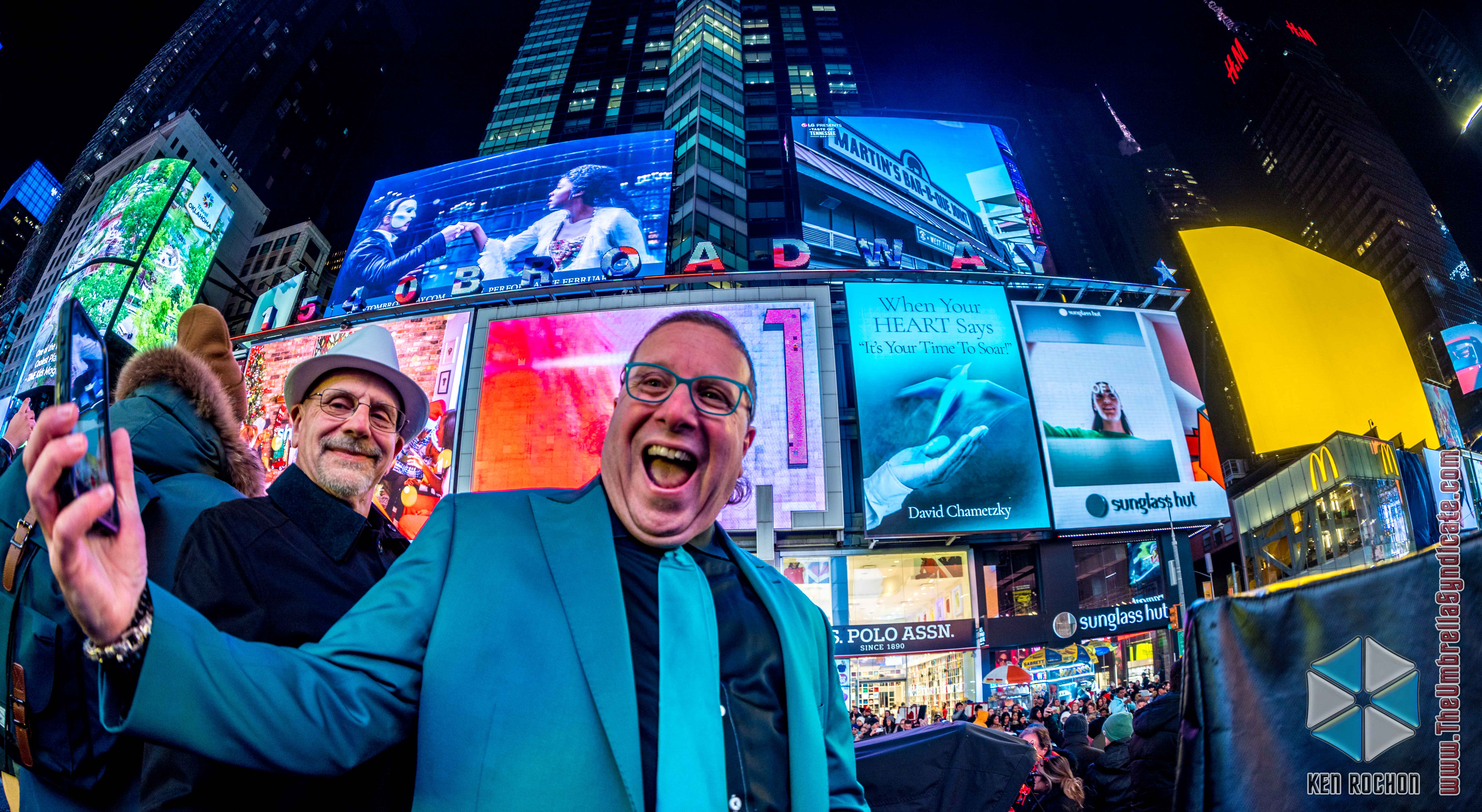 Man showing excitement in a selfie in front of NY Times Square billboards.